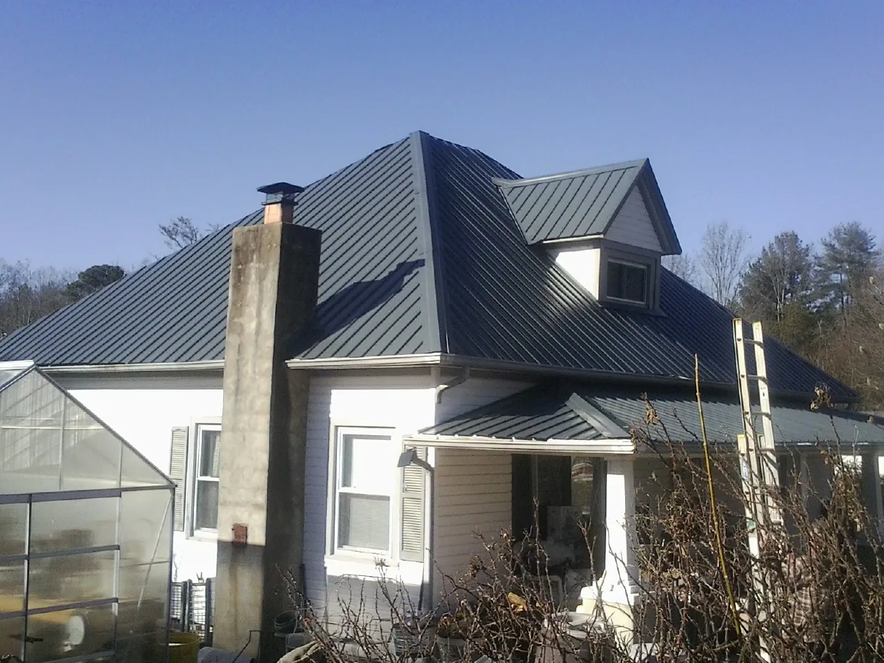 Dark blue standing seam metal roof on a white farmhouse with dormer — Slate & Tile Roof Repair by Roofing Brothers in Silver Star