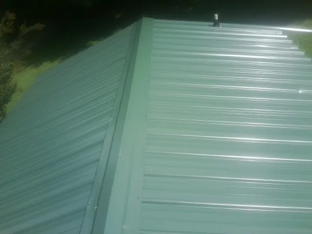New green metal panels meeting at the ridge of a roof — Flat Roof Repair work by our crew in Silver Star