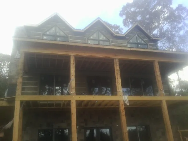 Dormers and porch framing on a large log home under construction — Roof Coating work by our crew in Silver Star