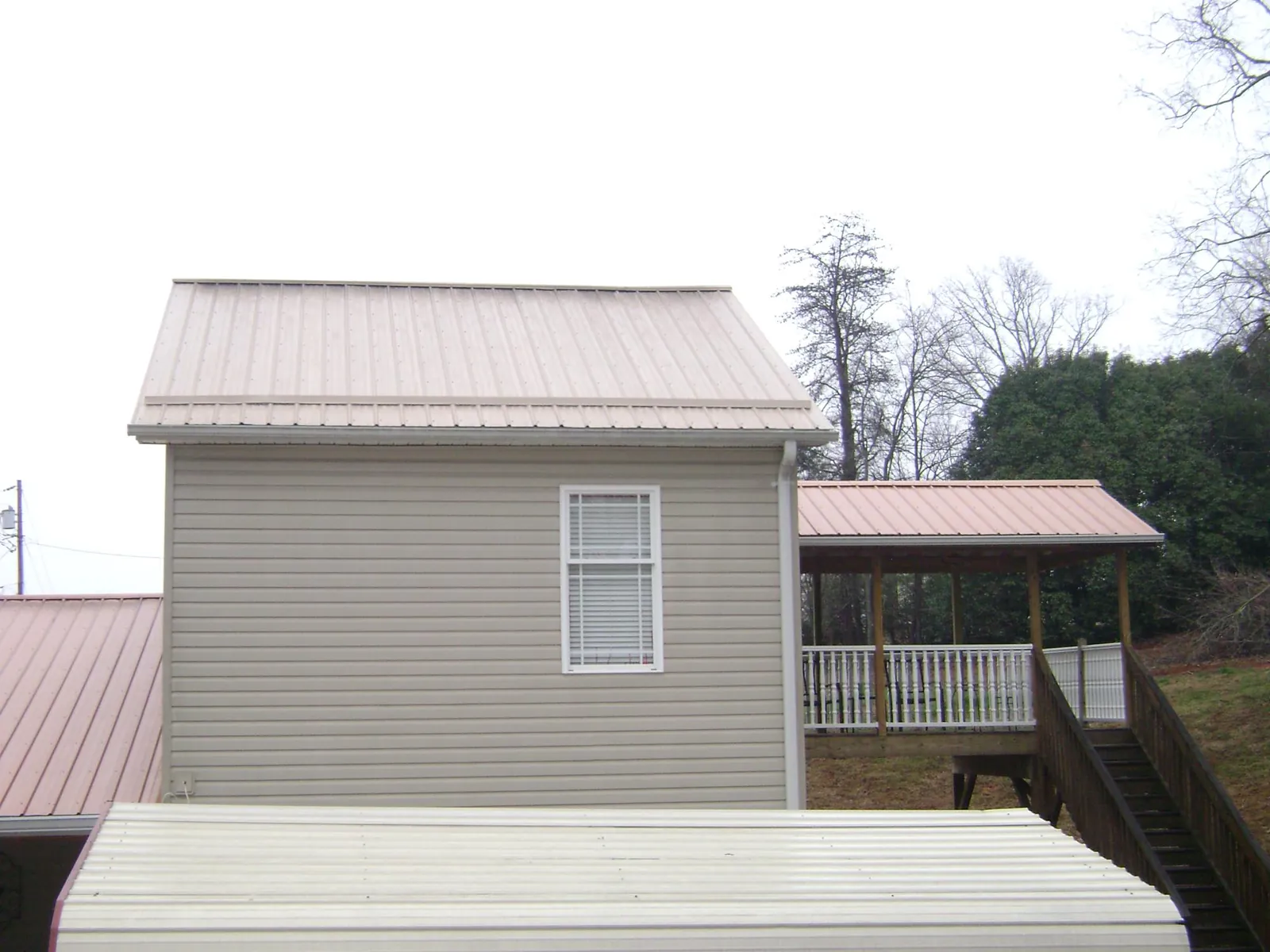 Tan metal roofs on a two story addition and attached porch, from a Roof Replacement job in Silver Star